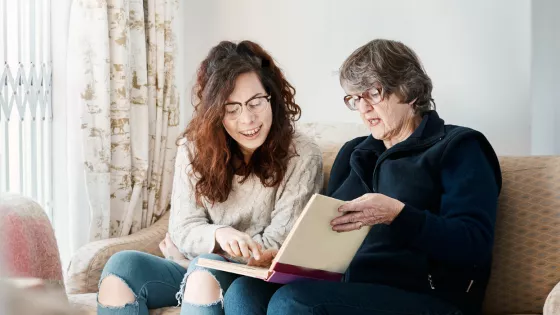 Older woman and young woman looks at a photo album together