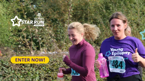 Two women running, smiling,  one with thumbs up to the camera  