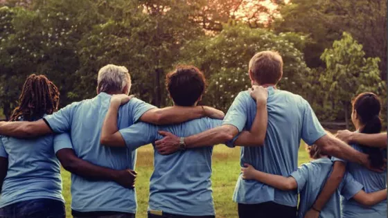 A row of people in matching blue t-shirts hold shoulders facing the sunset on the Autism and Epilepsy snapshot cover.