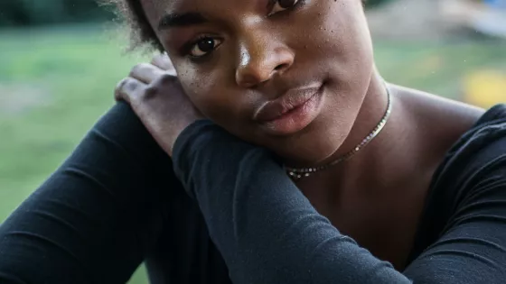 Young woman looks seriously to the camera, holding  one arm protectively across her body.