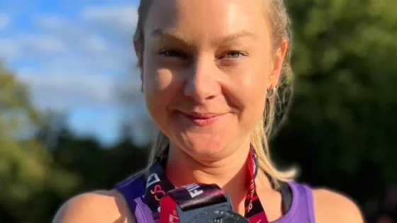 Young woman looks confidentially at the camera with her finishers medal around her neck
