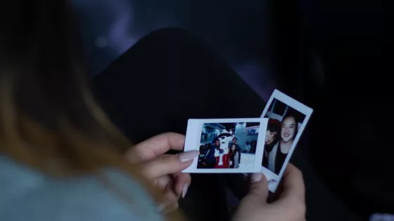 Looking over a woman's shoulder we can see she is looking at photographs