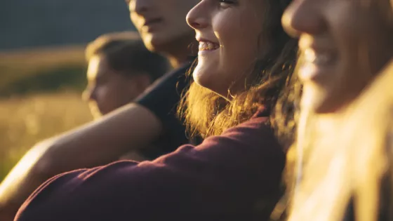 A group of young people at sunset smiling into the horizon