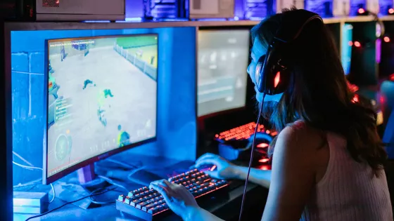 A photograpgh of a young girl playing playing video games, wearing a headset.