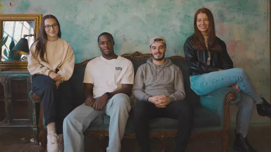 Photograph of four young people sat in a row looking directly at the camera