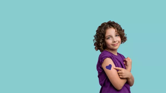 young girl in purple t-shirt with purple heart tattoo on her arm poses for the camera 