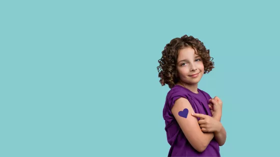 young girl in purple t-shirt with purple heart tattoo on her arm poses for the camera