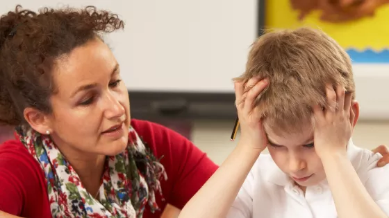 Photo of teacher supporting a school student who has his head in his hands