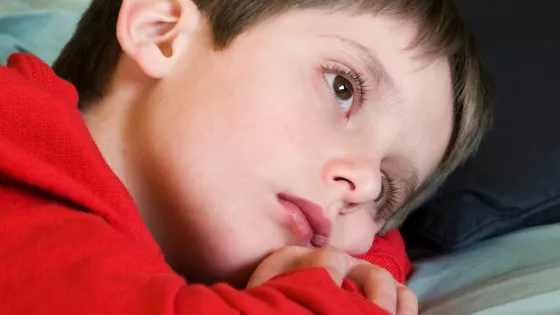 Photo of a boy lying down and staring into distance