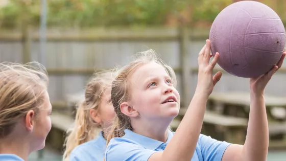Photo of school student playing netball with classmates