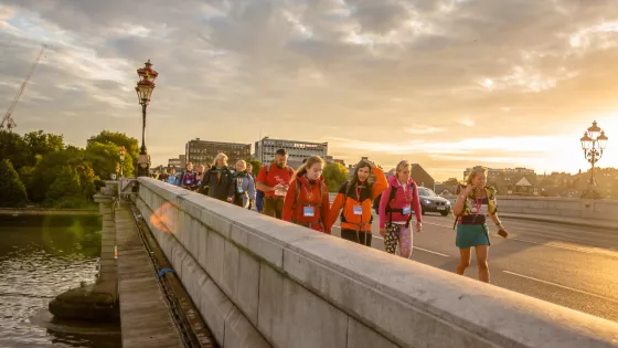 Group walking over bridge at sunset