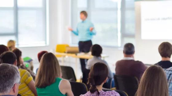 A photo of a trainer speaking to a room full of people