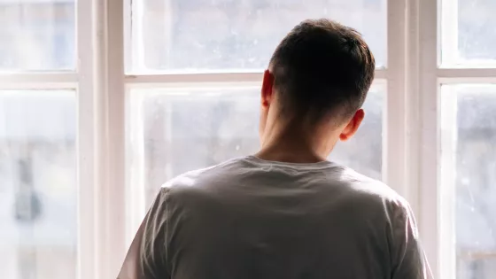 Photo of a young man looking out through a window 