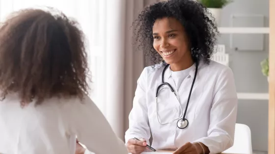 A medical professional smiles at a younger patient during a consultation.A medical professional smiles at a younger patient during a consultation.