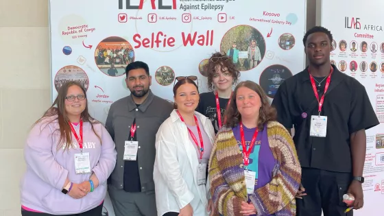 Young Epilepsy representatives stand in front of the International League Against Epilepsy selfie wall.