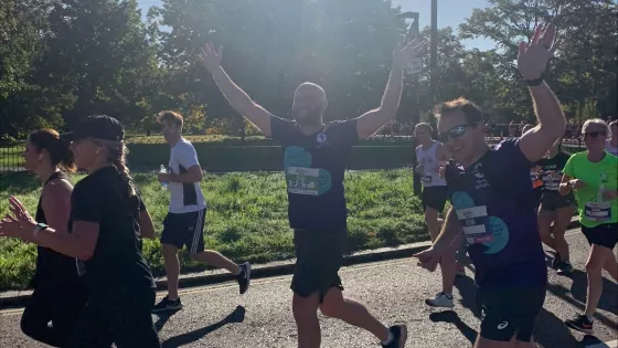 Two men in young epilepsy tops waving as they run by