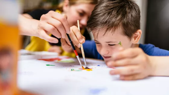 Specialist education teacher painting with young boy
