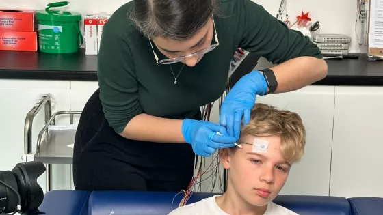 A boy is having electrodes fitted to his head for an EEG.