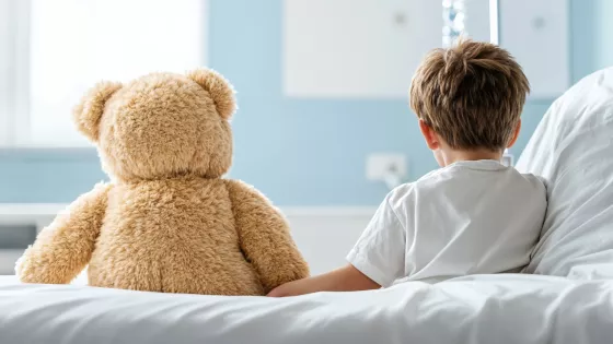 Child and teddy sitting on a hospital bed facing away