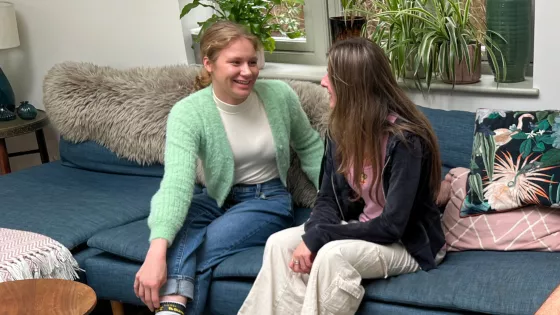 Two young girls socialise on a sofa together