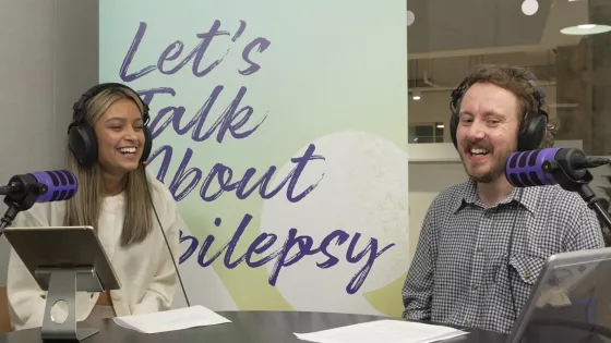 Young woman and man talk at a desk with microphones