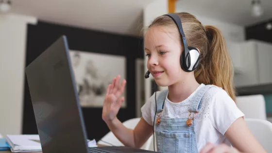 Young girl smiling and waving on a video call