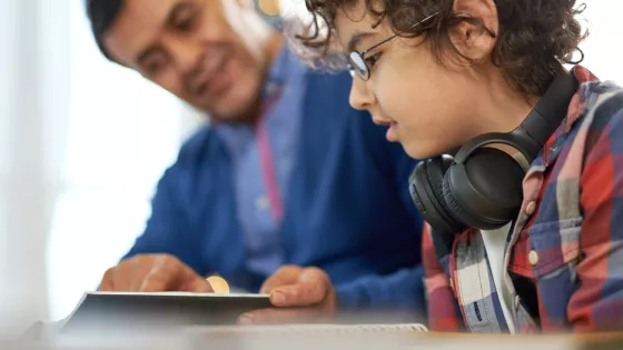 Young boy learning with an adult carer or parent