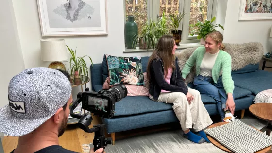Young people film a conversation on a couch.