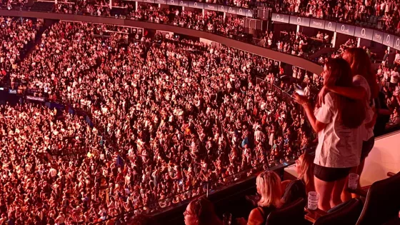 Two young girls look out to an audience at a concert.