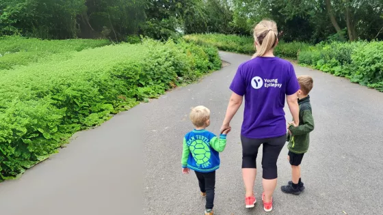 A mum wears a Young Epilepsy t-shirt whilst holding her children's hands.