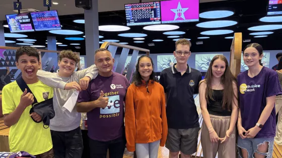 A group of young people and Young Epilepsy staff smile at a bowling alley.