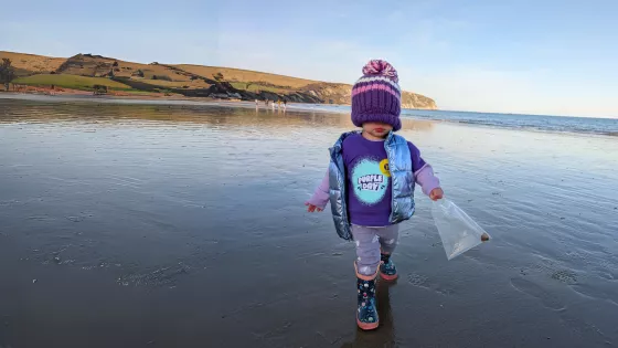 Young girl wearing a Young Epilepsy Purple Day t-shirt on a beach with a hat