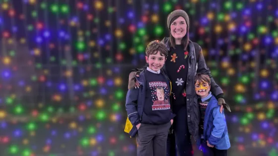 A family smiles together against a backdrop of fairy Christmas lights