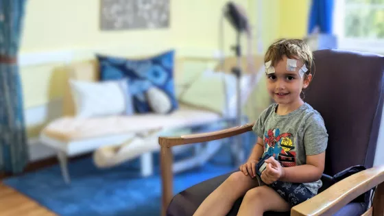Young boy, smiling in hospital with electrodes stuck to his head for an EEG.