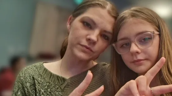 A mother and daughter give peace signs in a selfie.