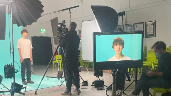 A young man is filmed on a blue background on a professional set.