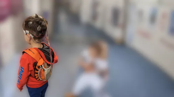 Young boy standing in hospital corridor with EEG electrodes on his head