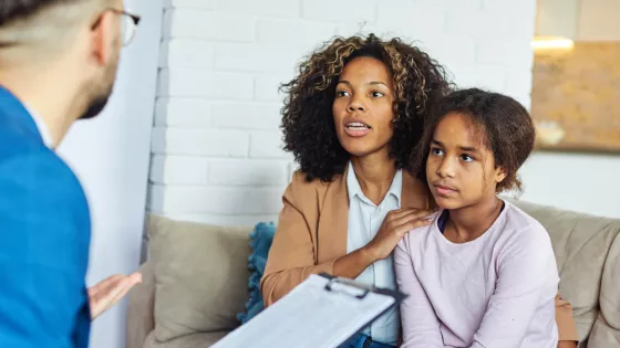 A doctor speaks to a mother and daughter about his notes.
