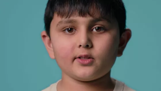 Young boy stood against a blue background