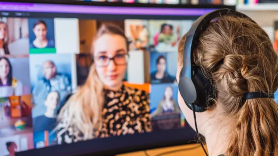 A young girl on a virtual call with other young people, wearing headphones.