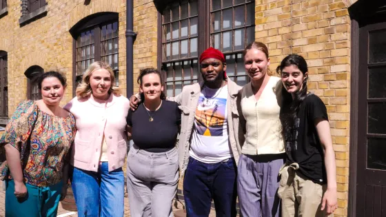 Young people stand arm in arm on a sunny day.