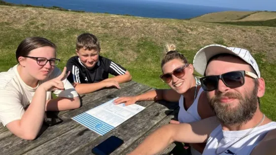 A family sits at a bench by the ocean.