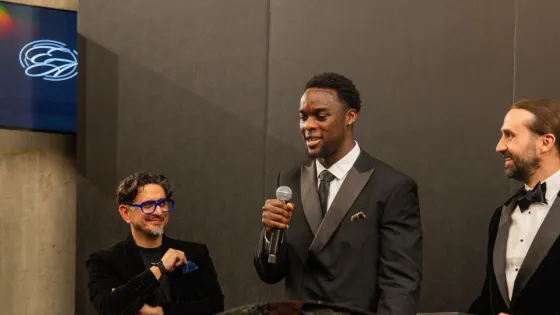 Two young men accept the Charity of the Year award from a third man at the Empowerment Awards.