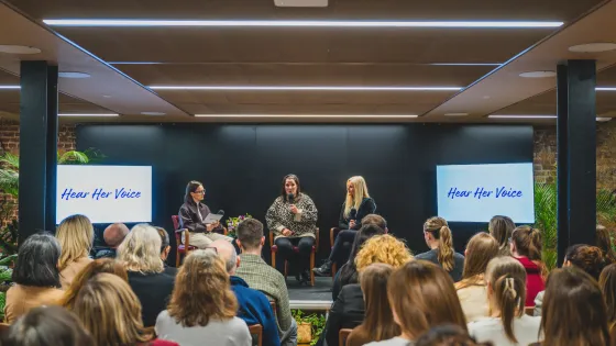 Hear Her Voice 2026 live event with panel speakers on stage addressing audience.