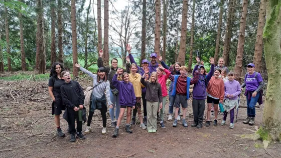 A group of hikers celebrate in a forest.