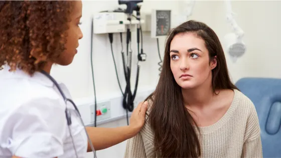 A young woman receives news from a medical professional.