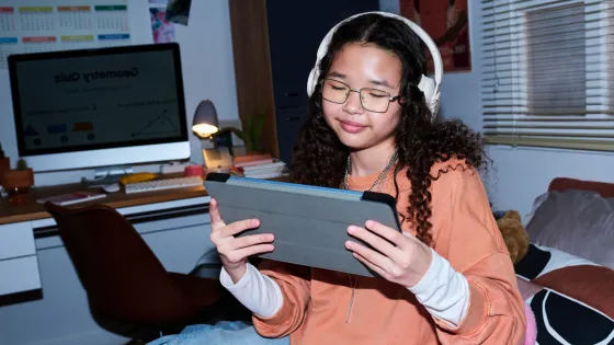 A young woman in headphones looks at a tablet.