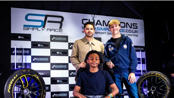 Two racing experts pose with a seated boy.