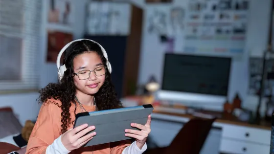 A teenager watches an iPad with headphones.