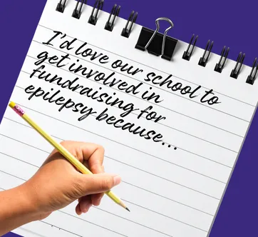 A child's hand writes on a notepad saying "I'd love our school to get involved in fundraising for epilepsy because..."